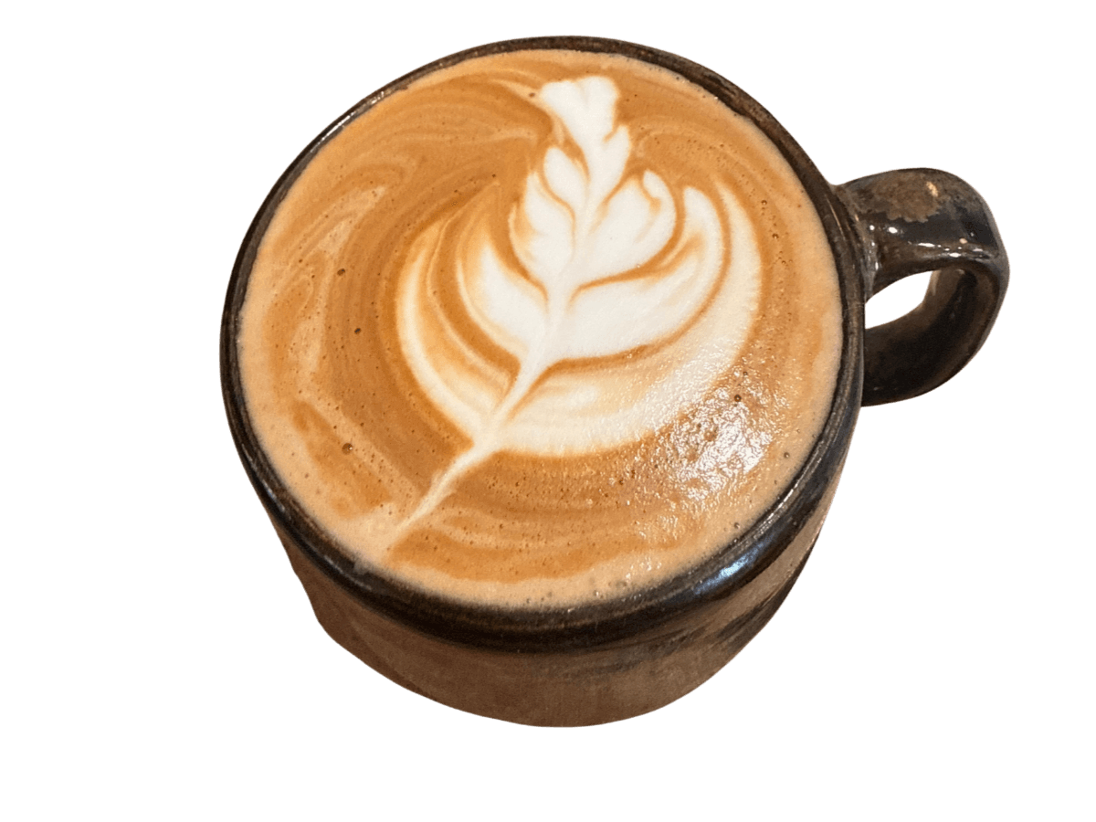 A latte with a fern-leaf pour, in a black ceramic mug