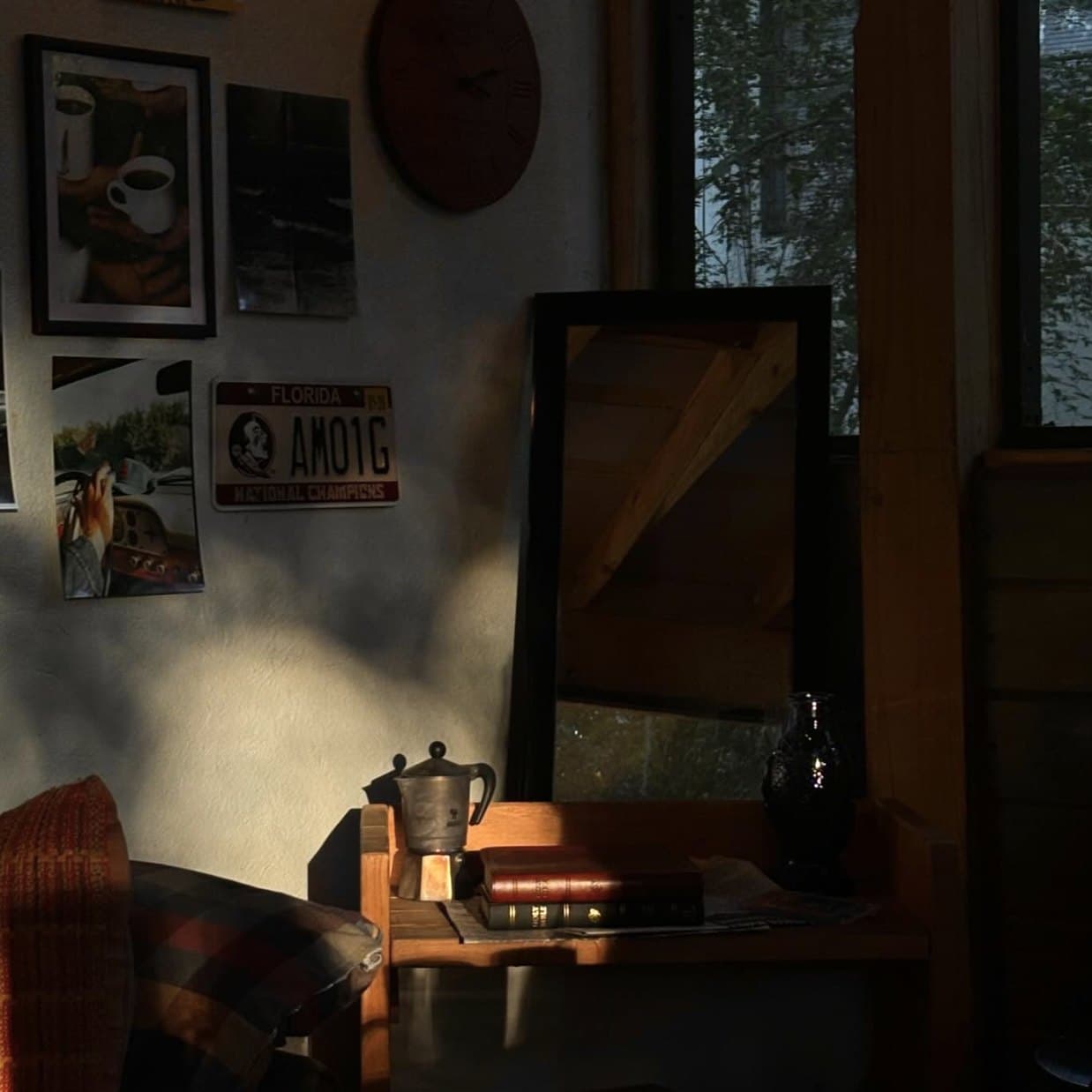 A sunlit corner at Baja Beans: moka pot, books, a mirror, and the wall of photos